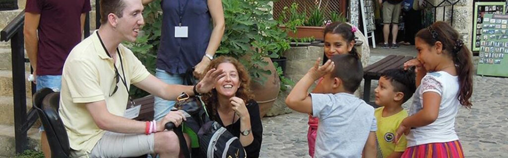 American on a scooter talks with local cypriot children