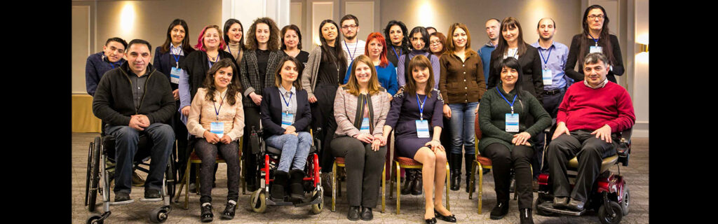 Group of participants with different types of disabilities pose for a group photo