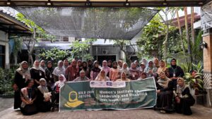A large group of Indonesian women gather holding a large sign announcing WILD