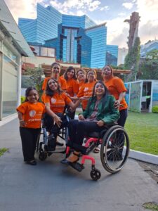 In Guatemala, 8 women with different disabilities happily pose in front of a dramatic blue glass building.