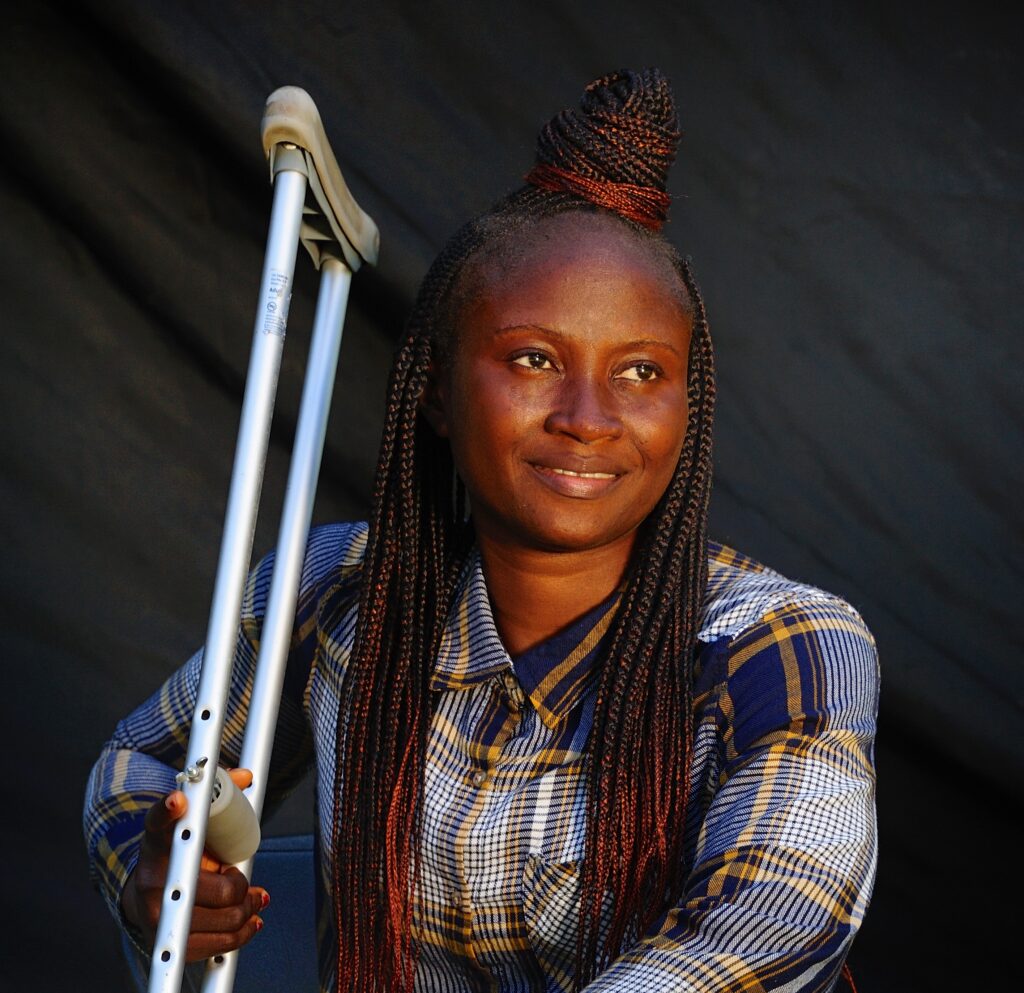 Princess smiles subtly and gazes upward. She holds a crutch in one hand