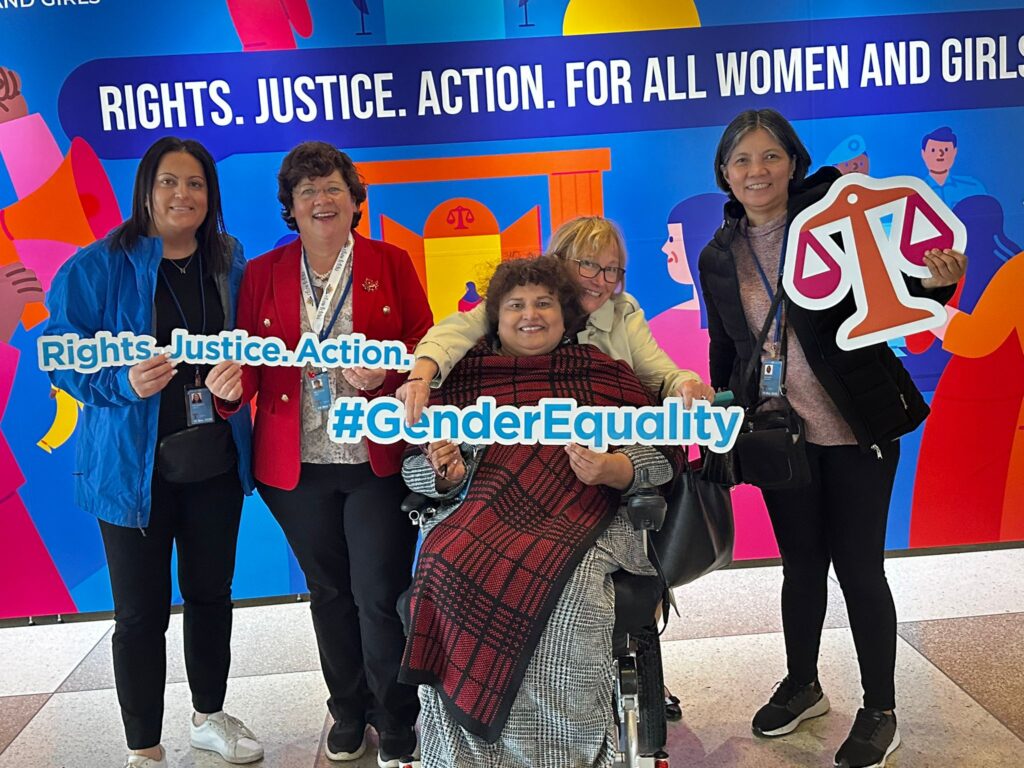 Meenu and colleagues at CSW holding signs for the scales of justice, "Rights. Justice. Action" and "#GenderEquality