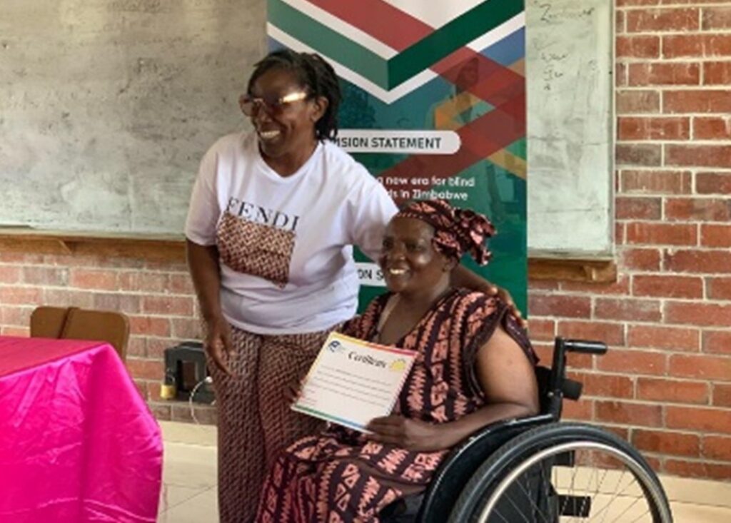 A WILD-Zimbabwe participant receives her certificate of completion from trainer Jules at the end of their training.